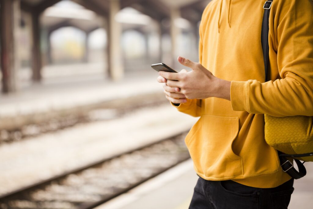 Passenger on railway platform looking at phone