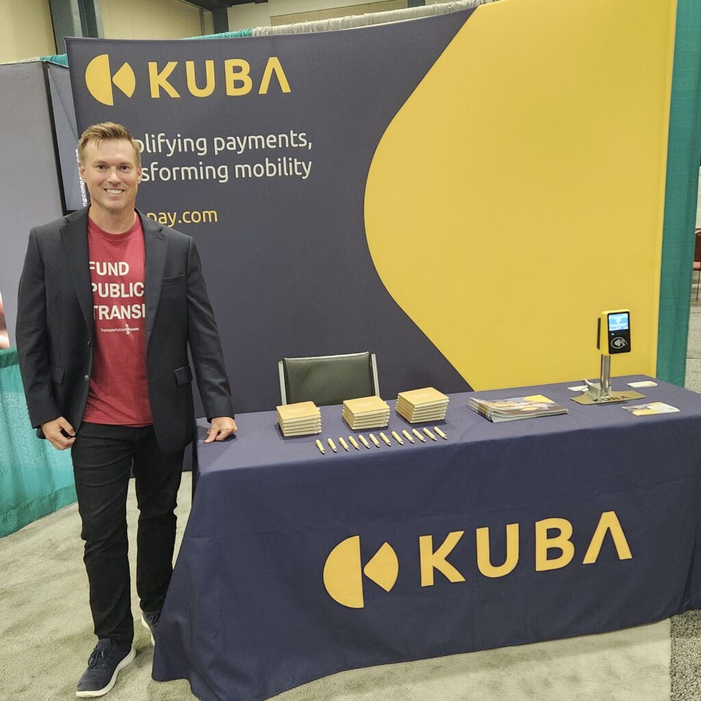 Kevin standing beside a table with a big Kuba logo on it